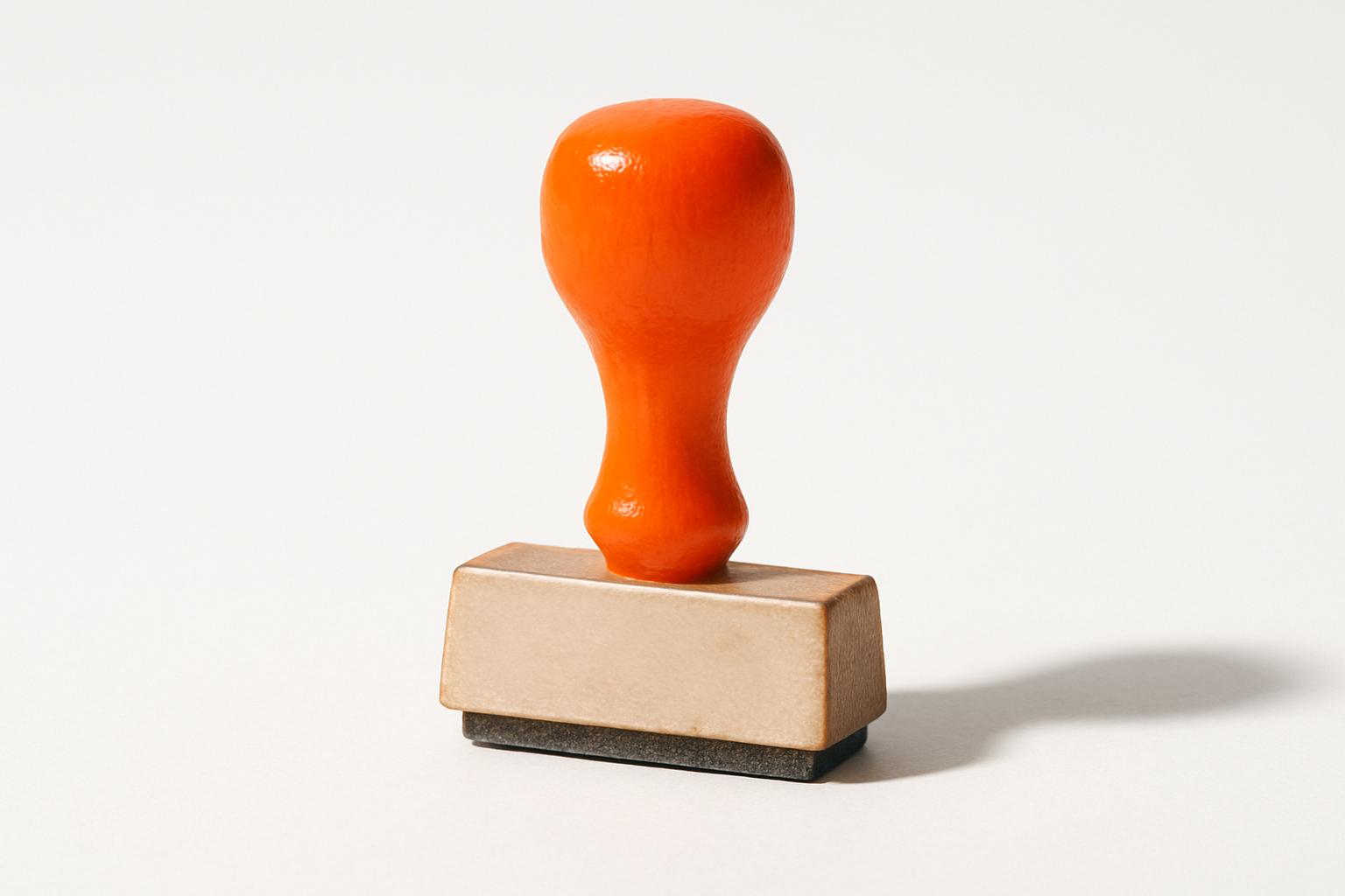 A worn wooden desk stamp with a blank carved block, its orange grip symbolizing unfinished ai transformations